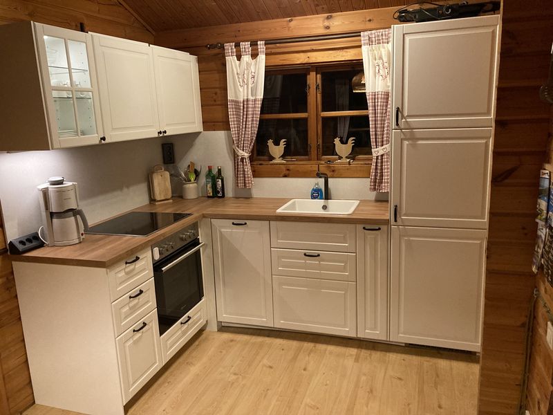 Helle Küche mit Backofen, Kochfeld, Kaffeemaschine und Kühl-Gefrierschrank