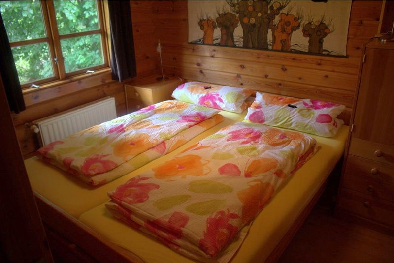 Elternschlafzimmer mit Doppelbett, Kleiderschrank und Fenster zum Wald