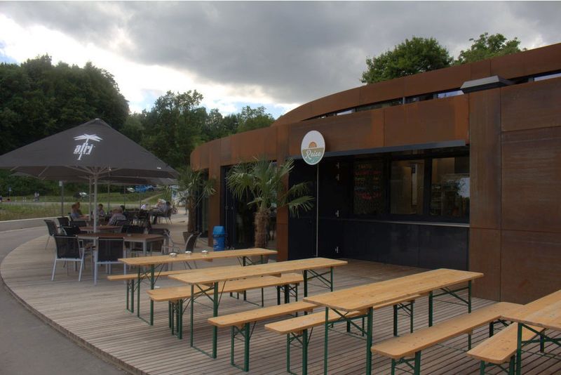 Strandbar mit Holzterrasse, Bierbänken und Sonnenschirmen